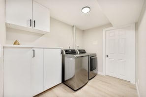 A laundry room with a washing machine, dryer, and cabinets.