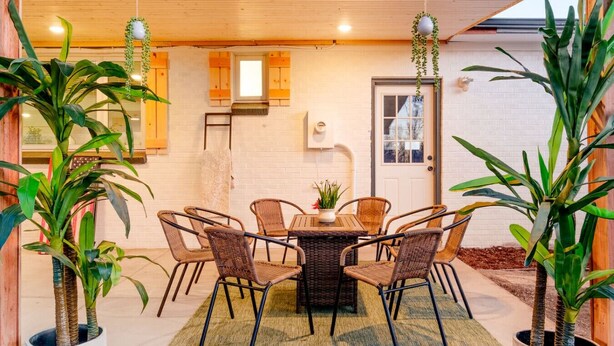 Un coin repas avec une table ronde et des chaises en osier, entouré de plantes en pot.