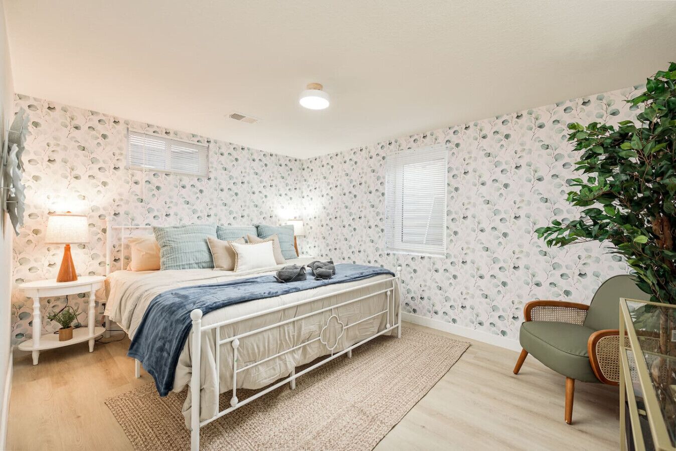 A bedroom with a bed, bedside table, lamp, and a chair.