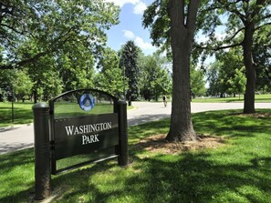 Schild für den Washington Park, mit einem deutlichen Weg und Bäumen im Hintergrund.