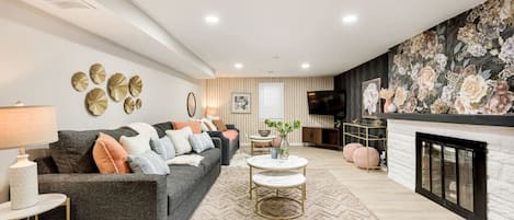 A modern living room with a grey sofa, a round coffee table, and a fireplace.