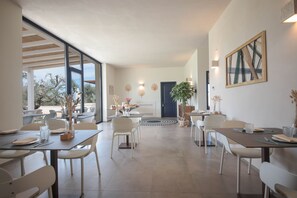 Un vaste espace dédié à la salle à manger, doté de meubles modernes et de grandes fenêtres offrant une vue sur l’extérieur.