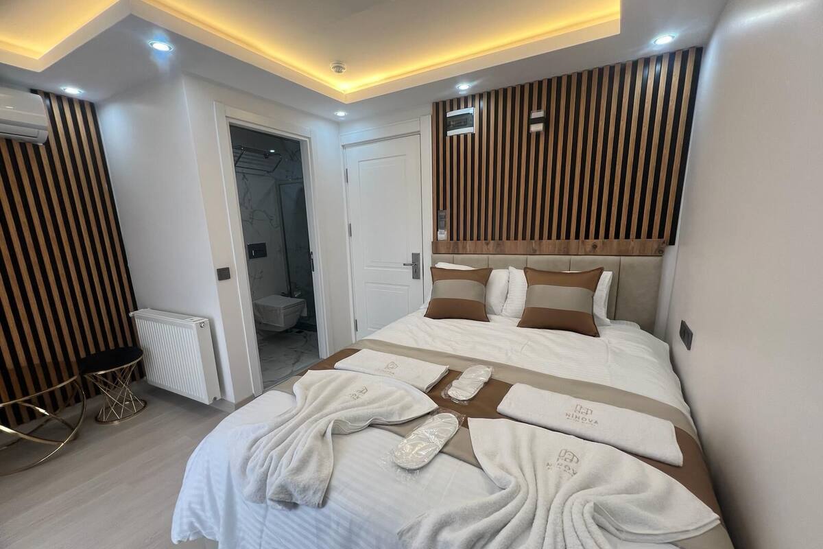 A modern hotel room with a large bed, a wooden headboard, and a walk-in closet.