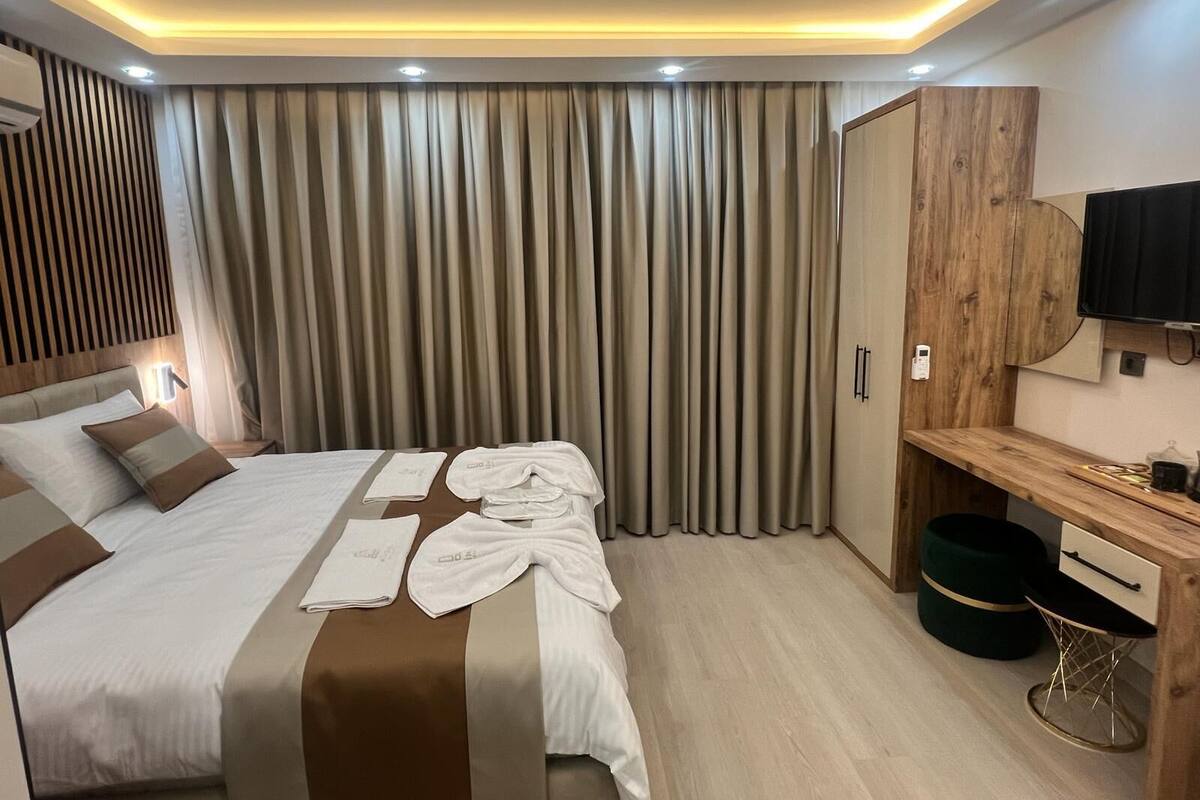 A modern hotel room with a large bed, a wooden desk, and a television.