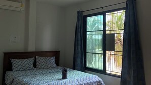 Ein Schlafzimmer mit Bett, einem fensterbelaubten Fenster, einer Klimaanlage und einer Hängeleuchte.