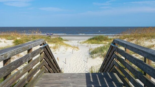 A wooden boardwalk leading to a sandy beach with dunes and a clear view of the ocean. - Villas By The Sea #184 - Oceanfront (Jekyll Island)