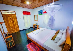 Un dormitorio con cama, mesita de noche, silla y mosquitero.