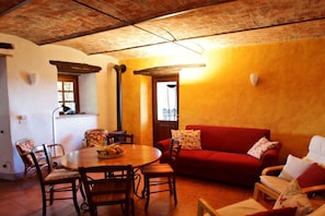 Una sala de estar acogedora con un sofá rojo, una mesa de comedor de madera y sillas.
