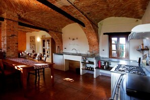 A kitchen with a brick ceiling, a dining area with a table and chairs, and a view of the adjacent room. - Nice apartment in Trassenheide (Bonvicino)
