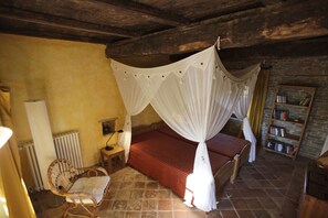 A room with a four-poster bed, a chair, a radiator, and a bookshelf. - Nice apartment in Trassenheide (Bonvicino)