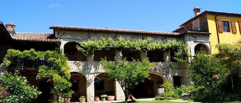 Un patio con un edificio que tiene ventanas de arco y techo de tejas.