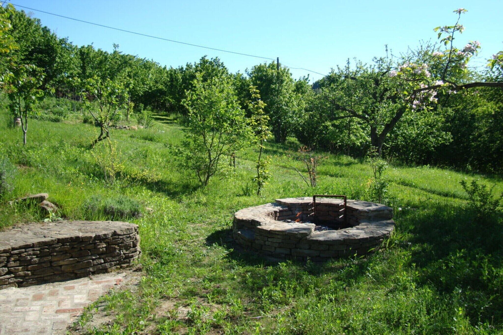 A stone structure in a grassy field with trees in the background.