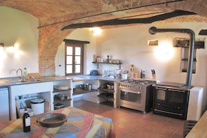 Una cocina con un arco de ladrillo, estufa, horno y distintos utensilios de cocina.