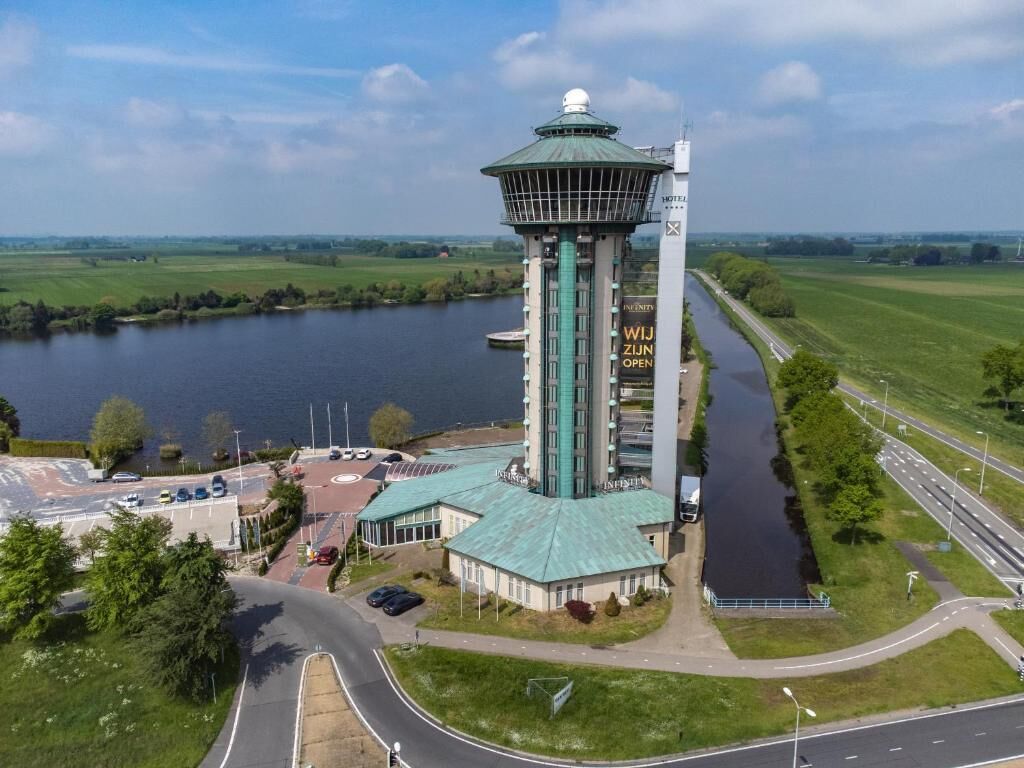 A tower hotel with a green roof, a control tower, and a river in the background.