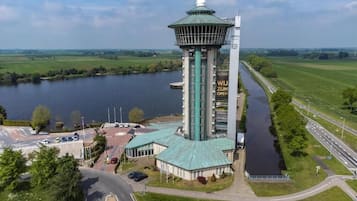 A tower hotel with a green roof, a control tower, and a river in the background.