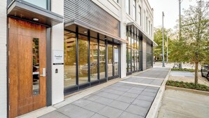 Un bâtiment moderne doté de grandes fenêtres en verre, d’une porte en bois et d’un chemin piétonnier pavé.