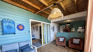 A cozy living area with a wooden ceiling, a blue sofa, two armchairs, and a woven light fixture. - Plein la vue (Saint-Pierre)
