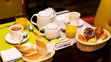 A breakfast setup with bread, pastries, coffee, and juice on a table.