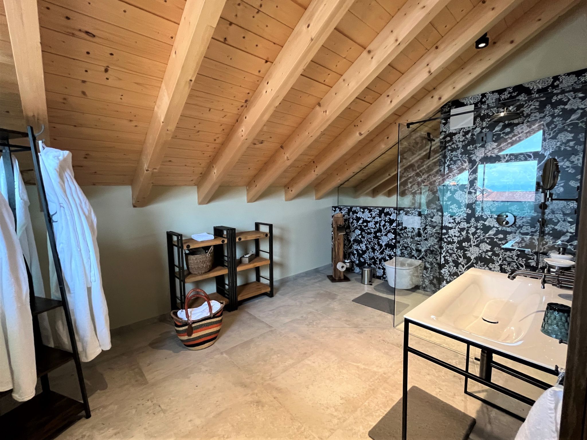 Un baño moderno con techo de madera, cabina de ducha con vidrio y vistas al exterior.