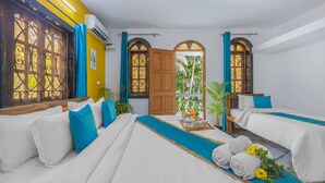 A hotel room with two beds, a wooden door, and a balcony with plants. - The Sequeira Guest House (Majorda)