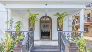 A staircase leading to a door with a cross above it, flanked by potted plants and a railing. - The Sequeira Guest House (Majorda)