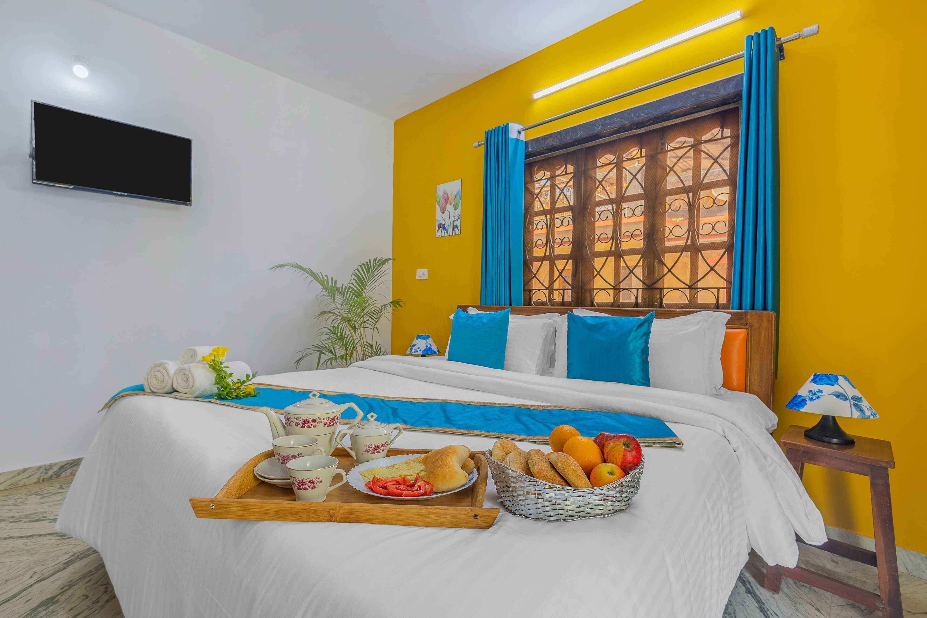 A hotel room with a bed, breakfast tray, and a TV on the wall.