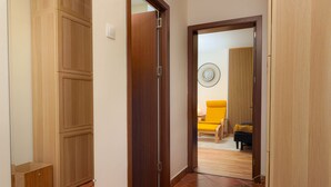 A hallway with wooden doors leading to a living area with a yellow chair and a black sofa. - Cozy 1-bedroom apartment in enjoyable Bucharest with WiFi, AC (București)