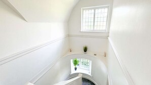 A narrow, white-walled stairwell with a small window at the top. - Zen 8-Bedroom Den in Edgbaston (Birmingham)