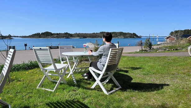 Iemand zit aan een tafel met uitzicht op een meer en een eiland in de verte.
