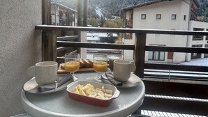Un balcon avec une table préparée pour le petit-déjeuner, offrant une vue sur un paysage montagneux.