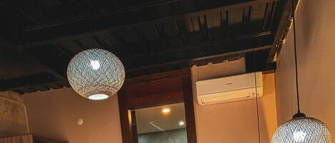 A bedroom with a wooden bed, a wooden wardrobe, and two hanging light fixtures.