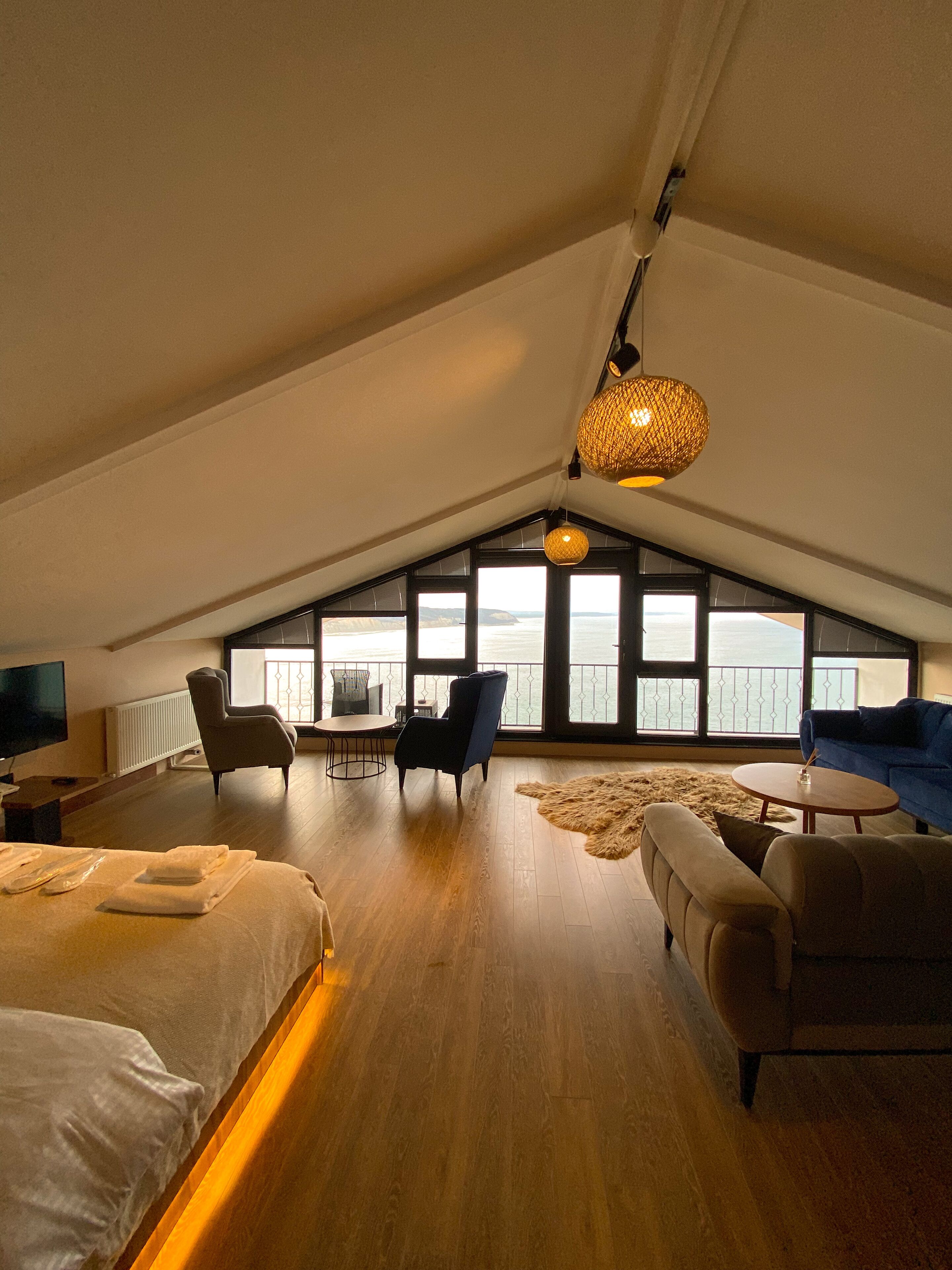 Een ruime loft slaapkamer met een groot dakvenster, een gezellige zithoek en een flatscreen televisie.