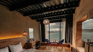 Ein modernes Schlafzimmer mit einem großen Bett, einem Schreibtisch und Blick auf den Ozean.