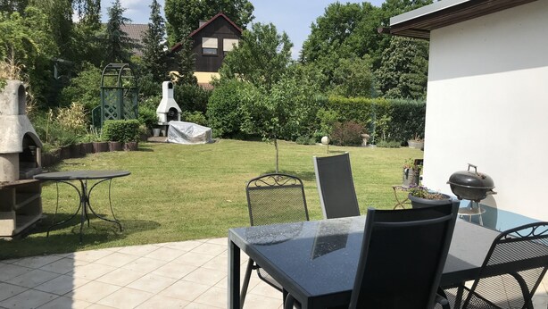 A patio area with a table and chairs, a barbecue grill, and a covered grill. - Ferienhaus "stück - Davon " Nr. 2 - Ruhig, Garten, Grillplatz, See, Schorfheide (Joachimsthal)