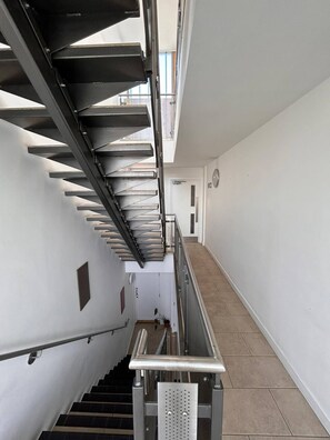 A modern interior with a staircase, metal railings, and a tiled floor.