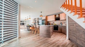 Una cocina moderna con una isla central, piso de madera e iluminación colgante.