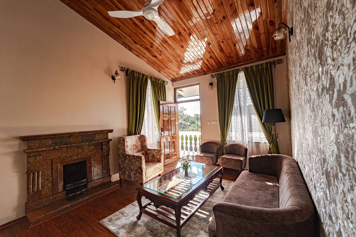A living room with a fireplace, wooden ceiling, and green curtains.