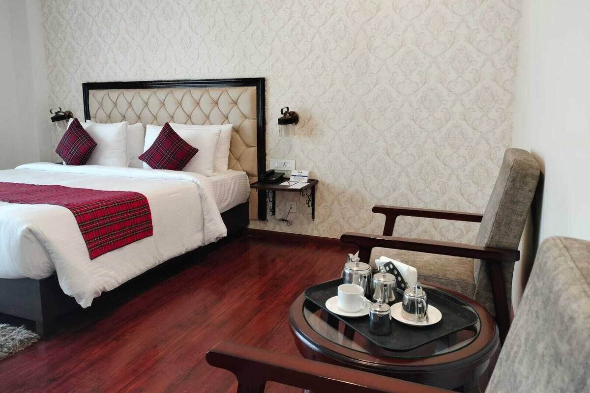 A hotel room with a bed, bedside table, and a small table with tea set.
