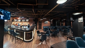 A bar area with a counter, bar stools, and a seating area with tables and chairs. - Windermere Hotel (Shillong)