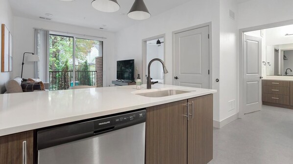 A modern kitchen with a dishwasher, a sink, and wooden cabinets.