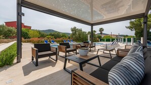 A covered outdoor seating area with lounge chairs and a pool, overlooking a scenic landscape. - Lovely apartment in Mrljane (Mrljane)
