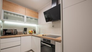 A modern kitchen with white cabinets, a wooden countertop, a built-in oven, and a microwave. - Lovely apartment in Mrljane (Mrljane)