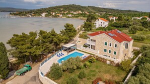 A stone building with a swimming pool, surrounded by greenery and a view of the sea. - Lovely apartment in Mrljane (Mrljane)