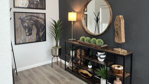 Un interior moderno con una pared oscura, una consola de madera y dos obras de arte enmarcadas.