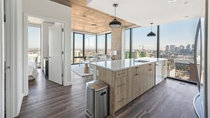 Een moderne keuken met een groot eiland, houten kasten en uitzicht op de stad.