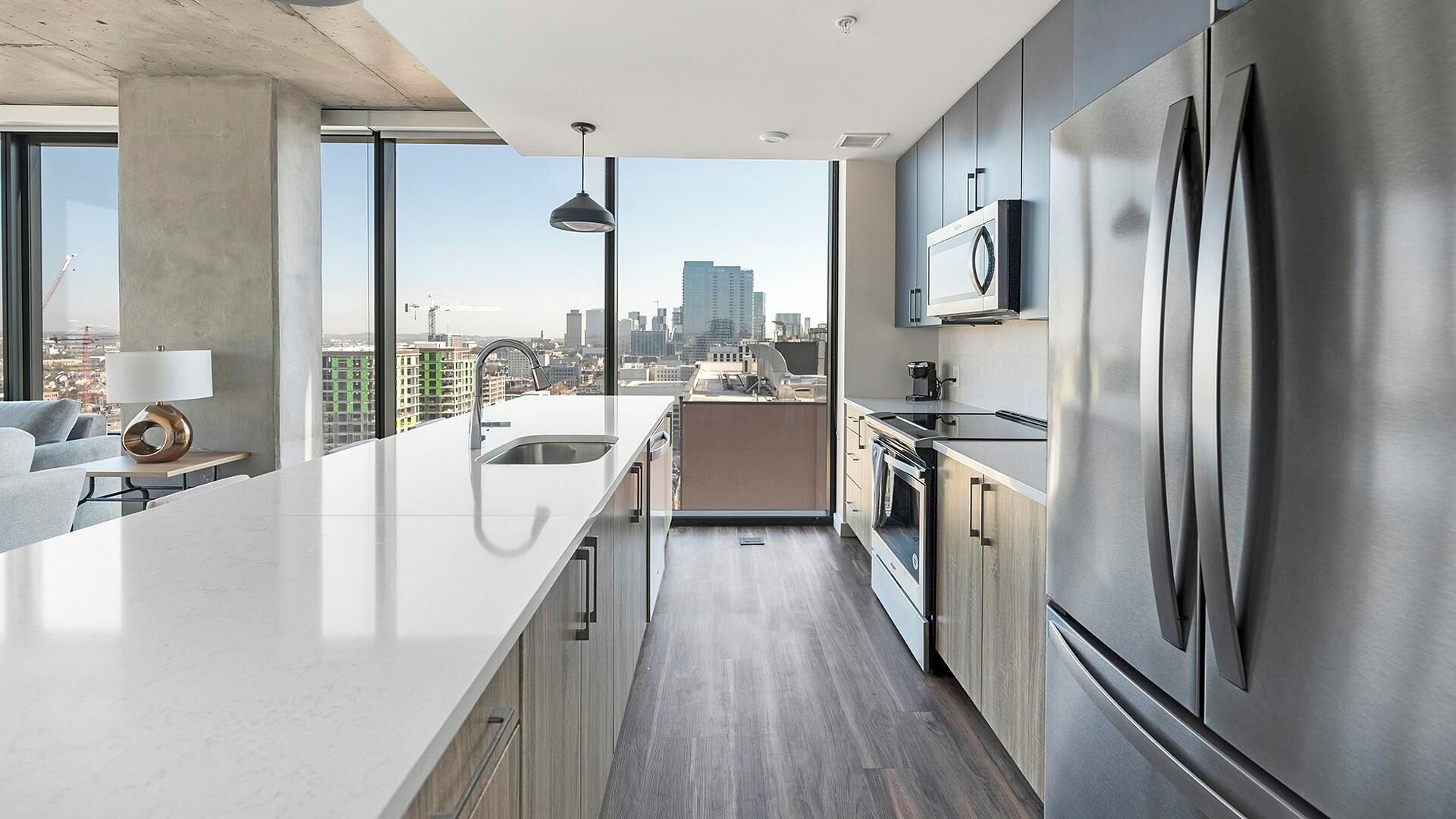 Een moderne keuken met een groot eiland, roestvrijstalen apparatuur en uitzicht op de stad.