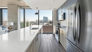 Een moderne keuken met een groot eiland, roestvrijstalen apparatuur en uitzicht op de stad.