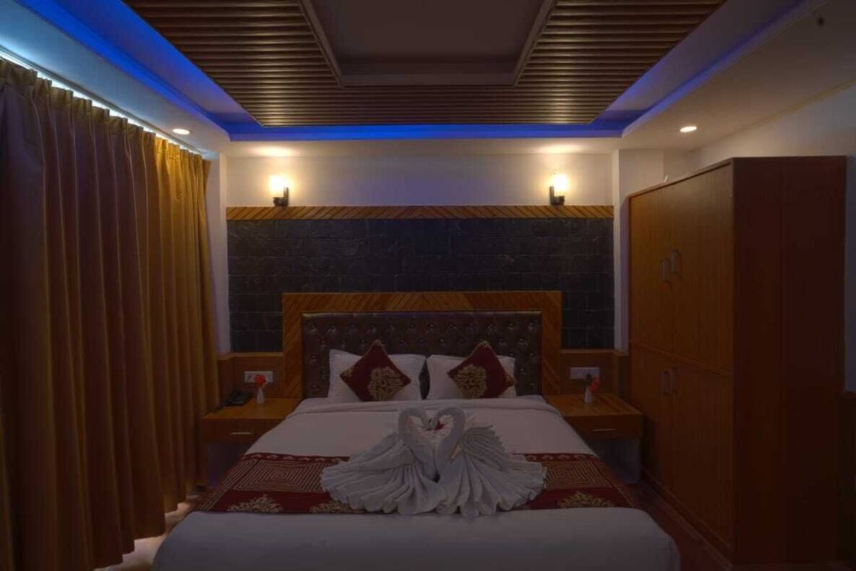 A hotel room with a large bed, a wooden headboard, and a stone accent wall.
