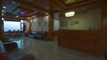 A reception area with a wooden reception desk, several chairs, and a large window offering a view of the mountains.