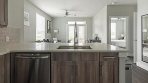 Une cuisine moderne dotée d’un îlot central, d’un lave-vaisselle intégré et de meubles de rangement en bois foncé.